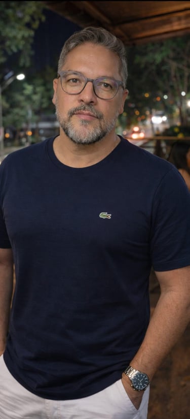 Portrait of a middle-aged man with glasses and a beard wearing a navy blue Lacoste t-shirt outdoors at night.