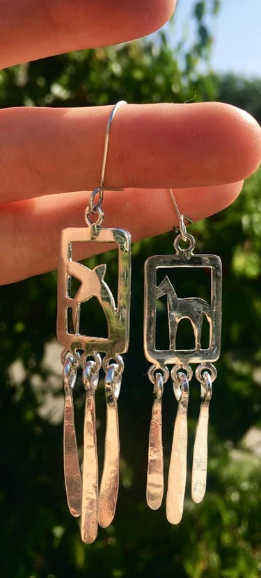 a pair of earrings with a horse and a swallow on it