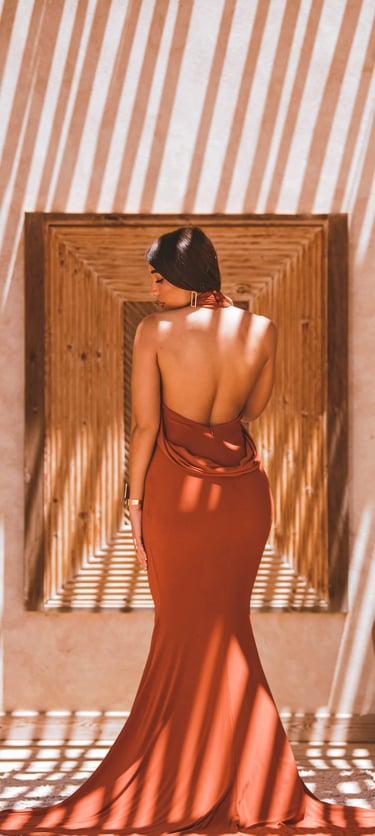 High-fashion portrait in Dakhla showing geometric shadow play on a resort wall with a model in an elegant backless dress.