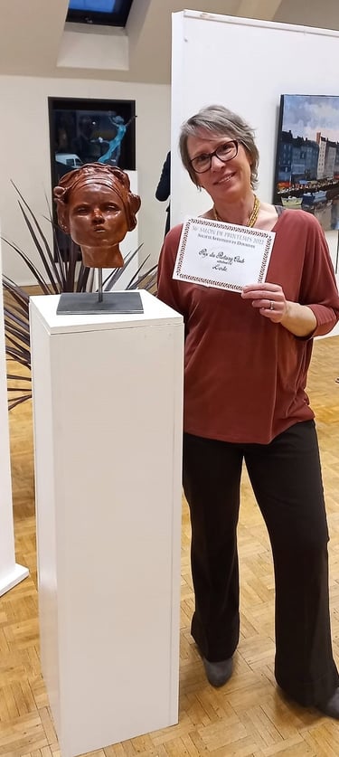 La sculptrice Lode à coté de sa sculpture Un Bisou? avec le prix du Rotary Club au salon de Dourdan