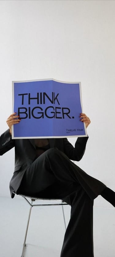Entrepreneur holding a “Think Bigger” sign symbolizing business growth and digital transformation fo