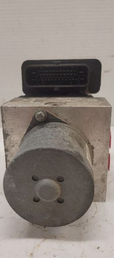 Used automotive ABS control module and hydraulic pump assembly for vehicle brake system repair.