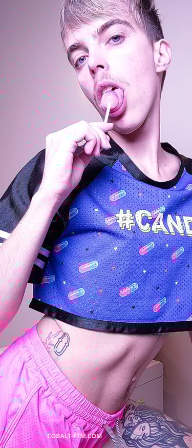 cobalt ftm, twink transboy prend une pose sexy en léchant une sucette, ftm porte short rose court