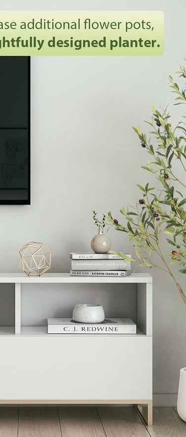 Artificial olive tree in a white planter standing next to a modern TV stand.