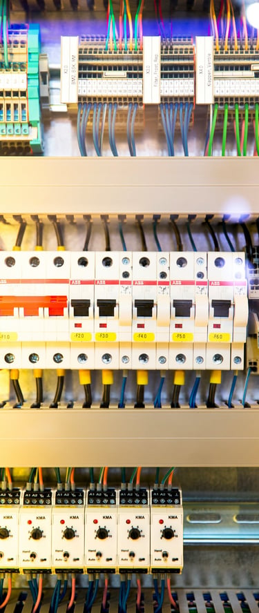 Industrial electrical control panel with circuit breakers, colorful wiring, and terminal blocks.