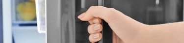 a person's hand holding a door handle on a refrigerator