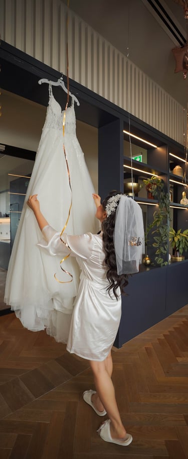 Bride in a silk robe reaching for her wedding dress before the ceremony, captured by Fred Art Studio