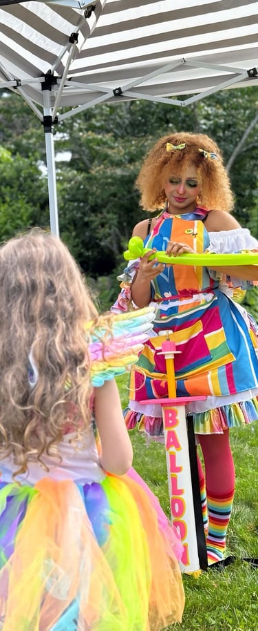 Balloon twister dressed in rainbow making a new shape