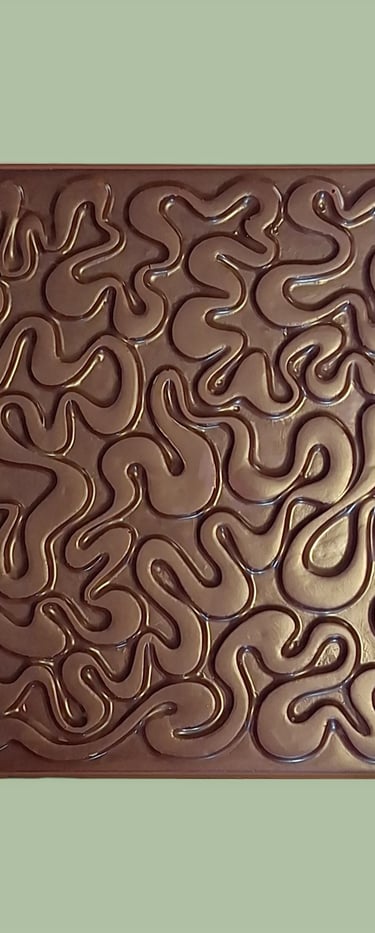A square dark chocolate bar with an intricate, wavy embossed maze pattern on a light green background.