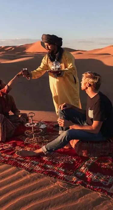 a man and woman sitting on a blanket in the desert