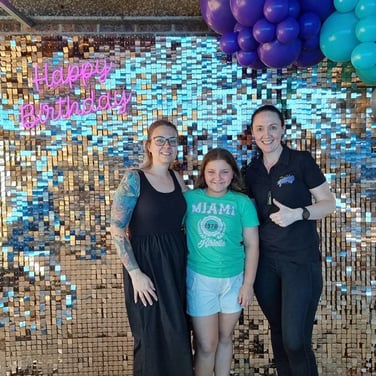 Violet and her mum in front of the rose gold shimmer wall and neon sign in Redlands.