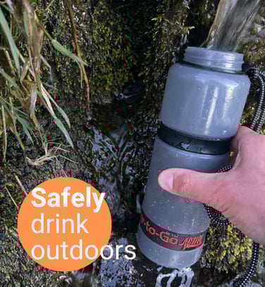a person holding a water bottle and drinking from a water bottle