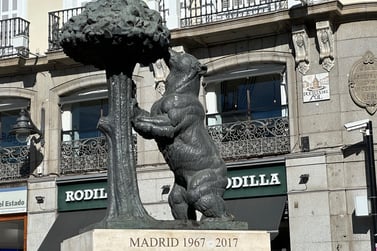 A statue of a bear leaning against a madroño tree