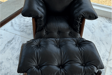 Uma poltrona elegante de couro na cor preta, totalmente restaurada e com brilho