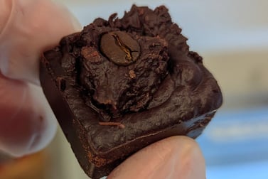 a person in gloves and gloves holding a piece of chocolate cake