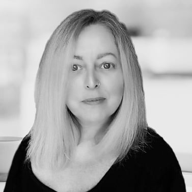 A black and white mid shot of a middle aged woman with long blonde hair and a nose ring.