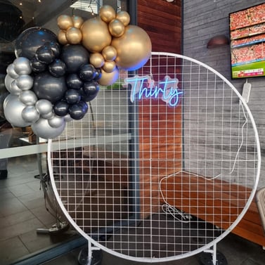 White circle mesh backdrop with a mini baloon garland and Thirty neon sign at the Chatswood Hill Tavern