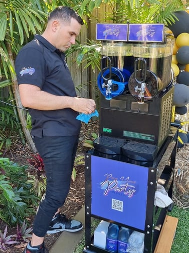 Kahn from SweetAz Co. doing the final cleaning touches to the slushie machine at a birthday party at a private home in Logan.
