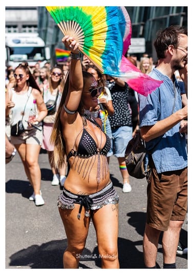 Eine spärlich bekleidete Frau mit einem Regenbogenfächer.
