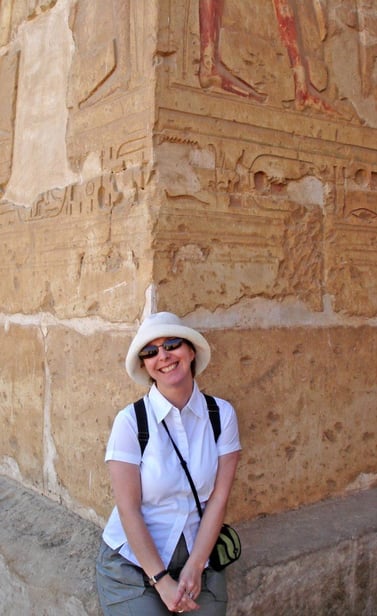 d ann hall in a hat and sunglasses standing in front of a large Egyptian wall