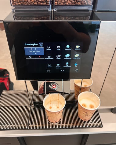 Thermoplan Black&White 4c espresso machine brewing two milk-based drinks simultaneously.