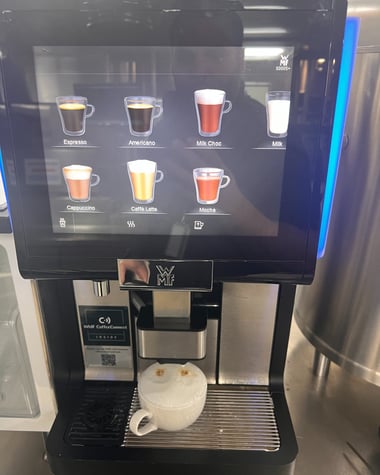Schaerer machine preparing a cappuccino with milk froth in a ceramic cup.