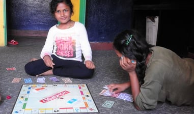 a girl sitting on the floor playing a game of monopoly