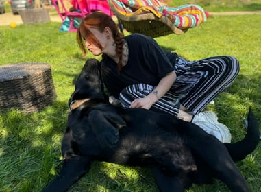 personne embrassant un chien labrador noir dans l'herbe