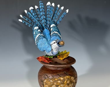 a blue bird sitting on top of a wooden bowl