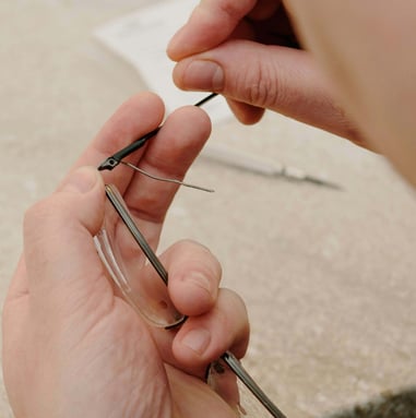 les mains d'un opticien qui change une branche de lunettes.