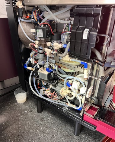 Internal components and valves exposed during super-automatic espresso machine repair