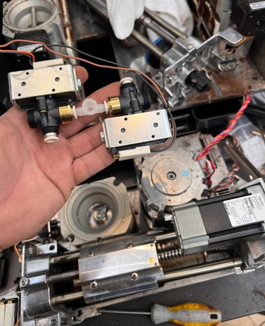Close-up of solenoid valves removed for replacement during Mastrena 2 espresso machine maintenance.