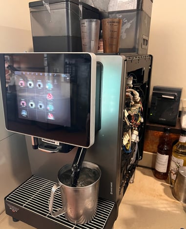 Franke A600 super-automatic espresso machine dispensing hot water into pitcher during maintenance.