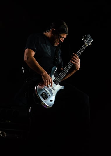 Robert Trujillo playing a guitar in a dark room