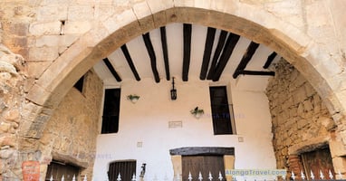 A stone arched outdoor terrace with logs on the ceiling in Espluga