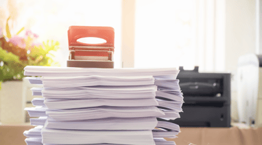 a stack of papers and a phone on a desk