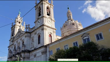 white building with a dome and twin bell towers are seen from tram 28 wagon in Lisbon