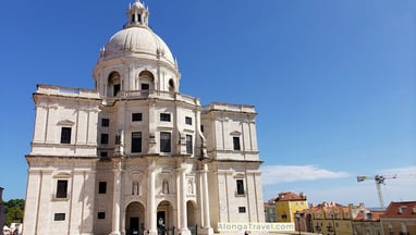 White monumental building with massive white dome nearby tram 28 route as seen from Alfama barrio