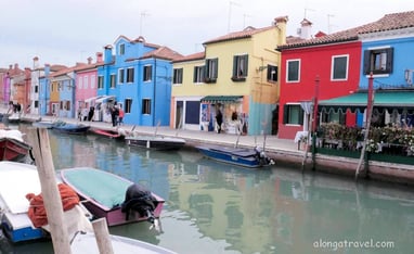 A row of colorful old buildings along a canal on Burano from a solo trip visit