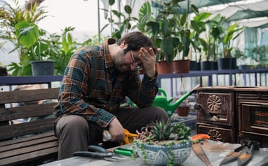 Frustrated gardener rubbing his head