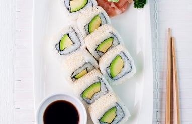 a plate of sushi rolls and chopsticks