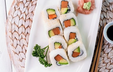 a plate of sushi rolls with chopsticks and sauce