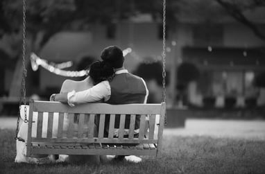 a couple sitting on a swing set in a park