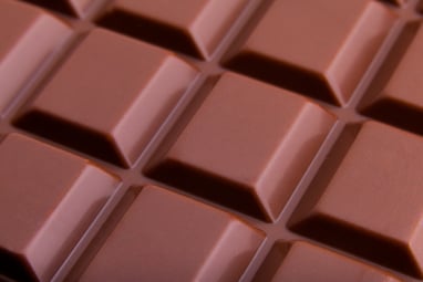 Close up macro view of the top of a milk chocolate bar zoomed in on the squares