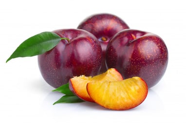 3 whole purple plums behind 2 slices of yellow plums
