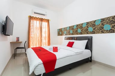 flazale reddoorz flash sale a bed with a red and white bedding and a television