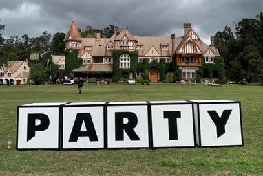 Vista del palacete en un entorno campestre, con parte del cartel de bienvenida "Penta Party" 