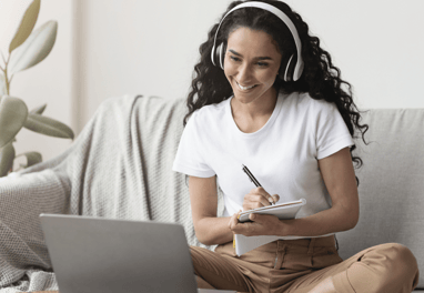 a woman sitting on a couch with a laptop and headphones