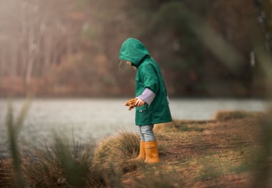a little girl in a green raincoat and boots