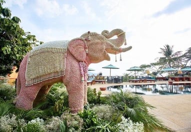 a pink elephant statue in a garden